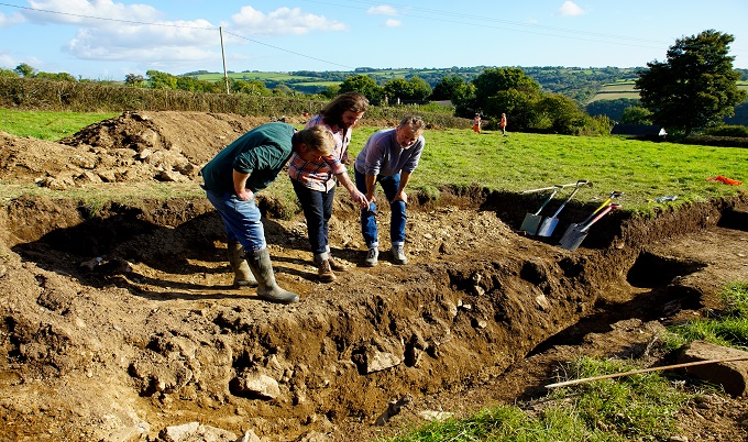 three people looking into a trench in the ground three people looking into a trench in the ground